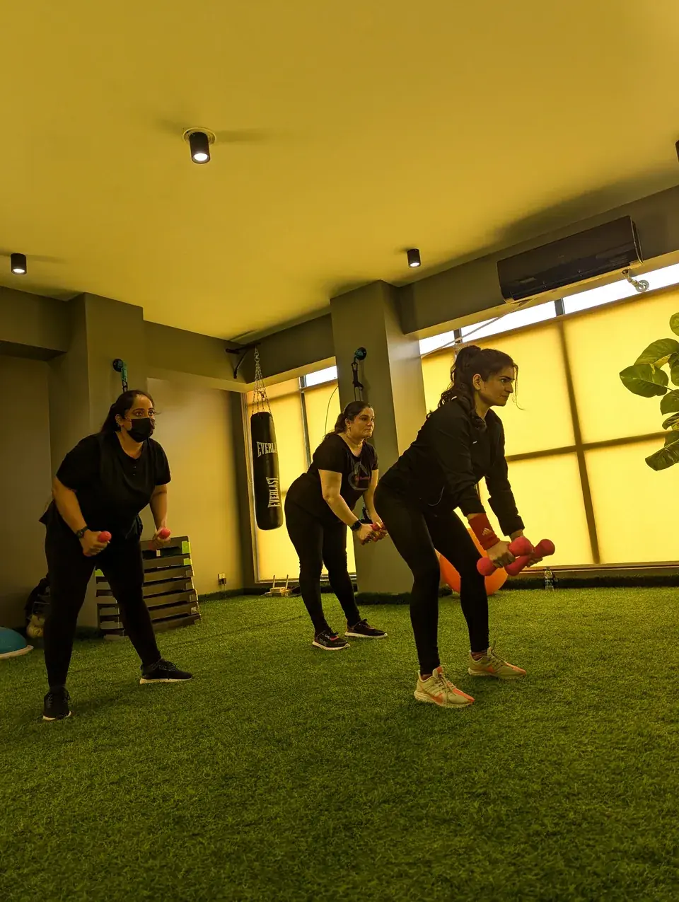 Women exercising with handheld weights on a green studio floor